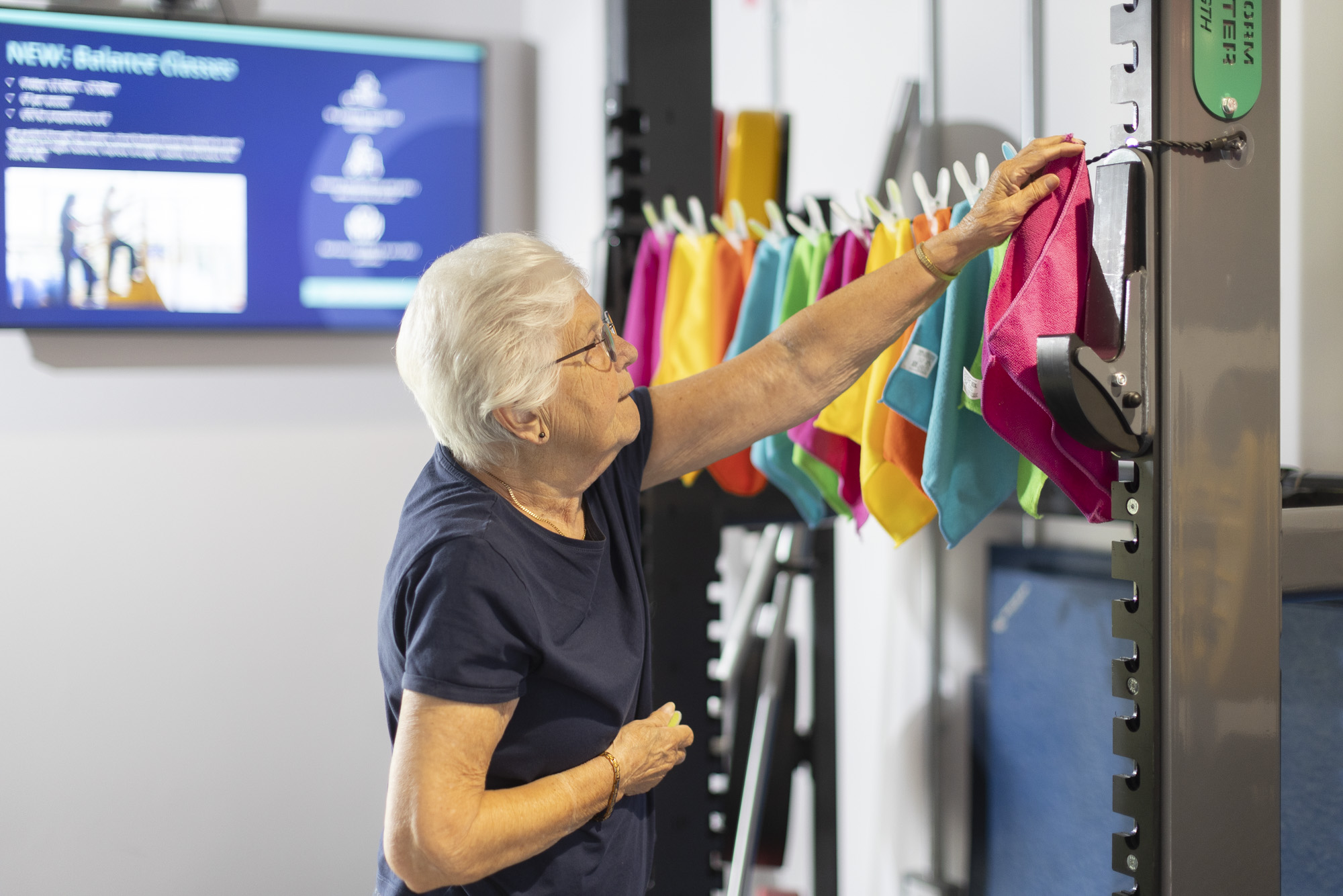 Elderly woman performing functional exercise involving hanging clothes on a washing line