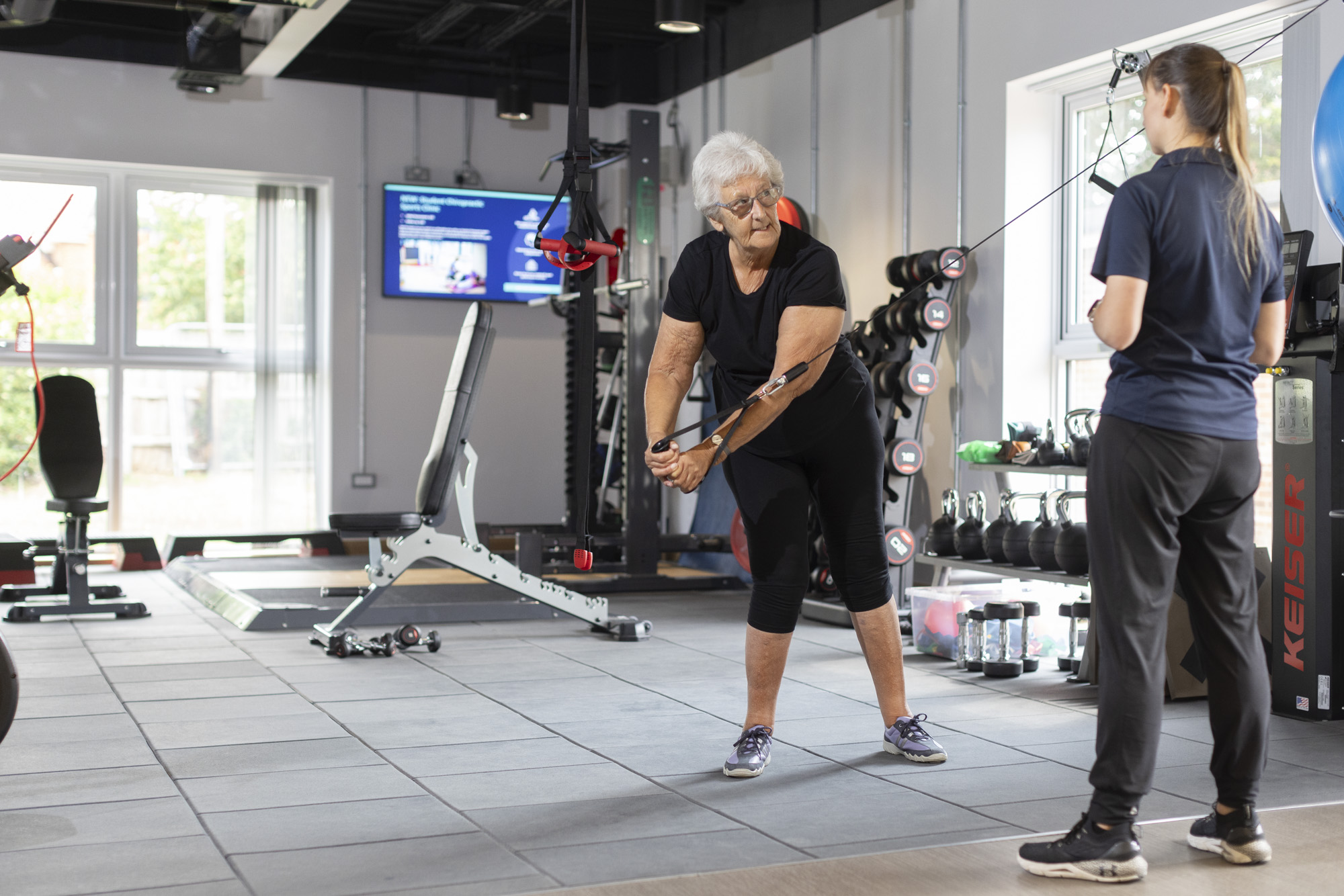 patient using exercise equipment under the supervision of her physiotherapist