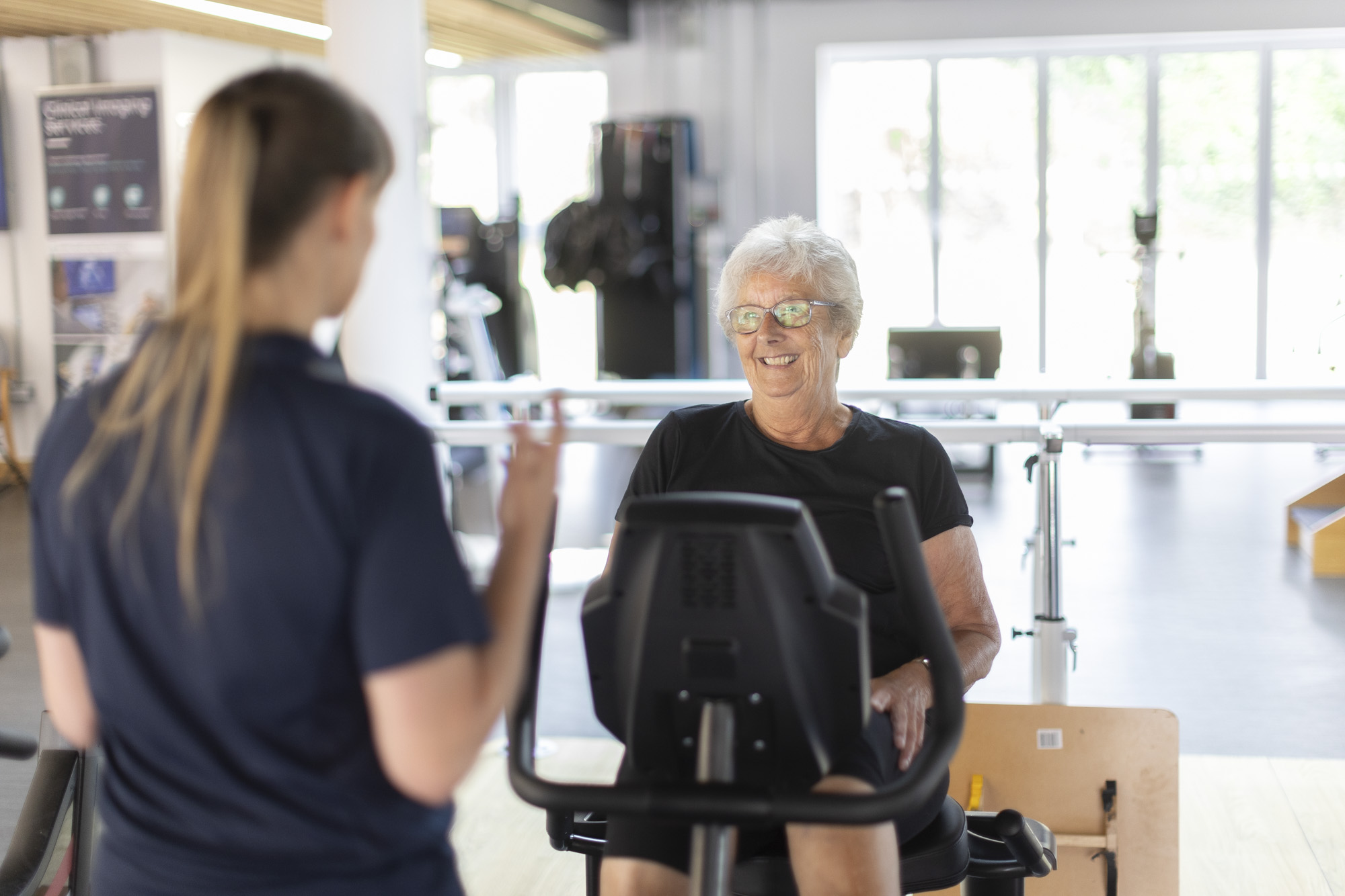 Elderly patient smiles looking at consultant giving her encouragement and instruction