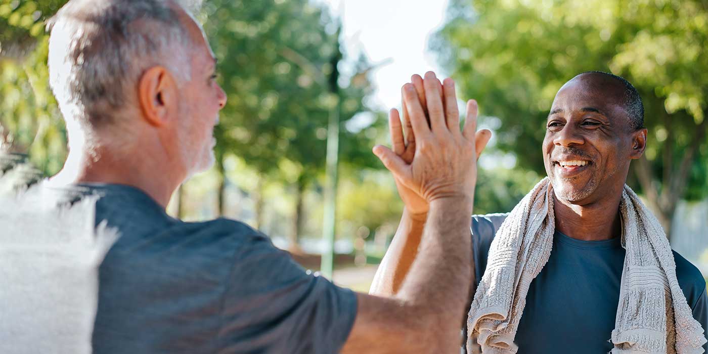 two middle aged men high fiving outside after some exercise