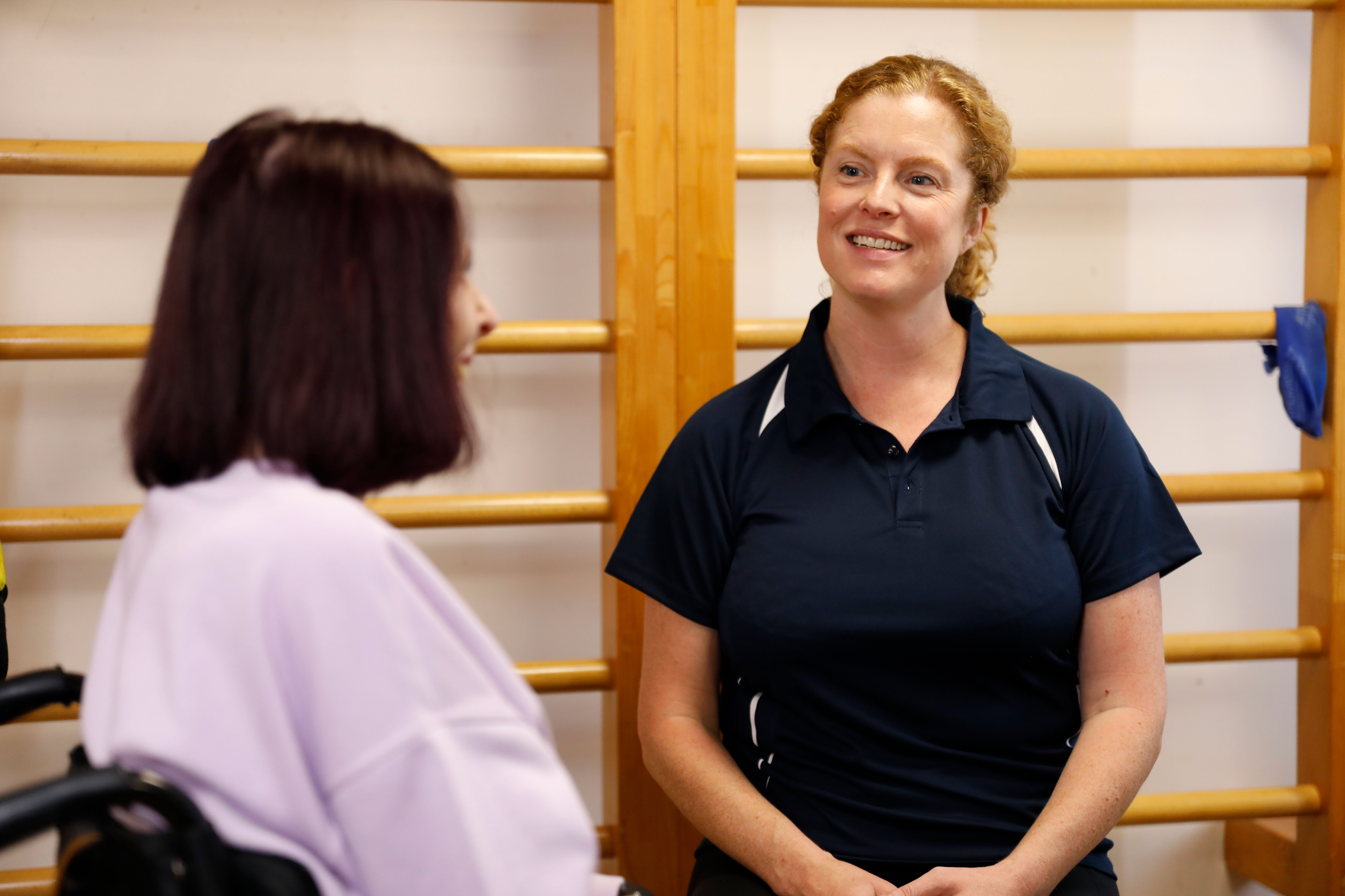 Neurological physiotherapist consulting female patient in wheelchair