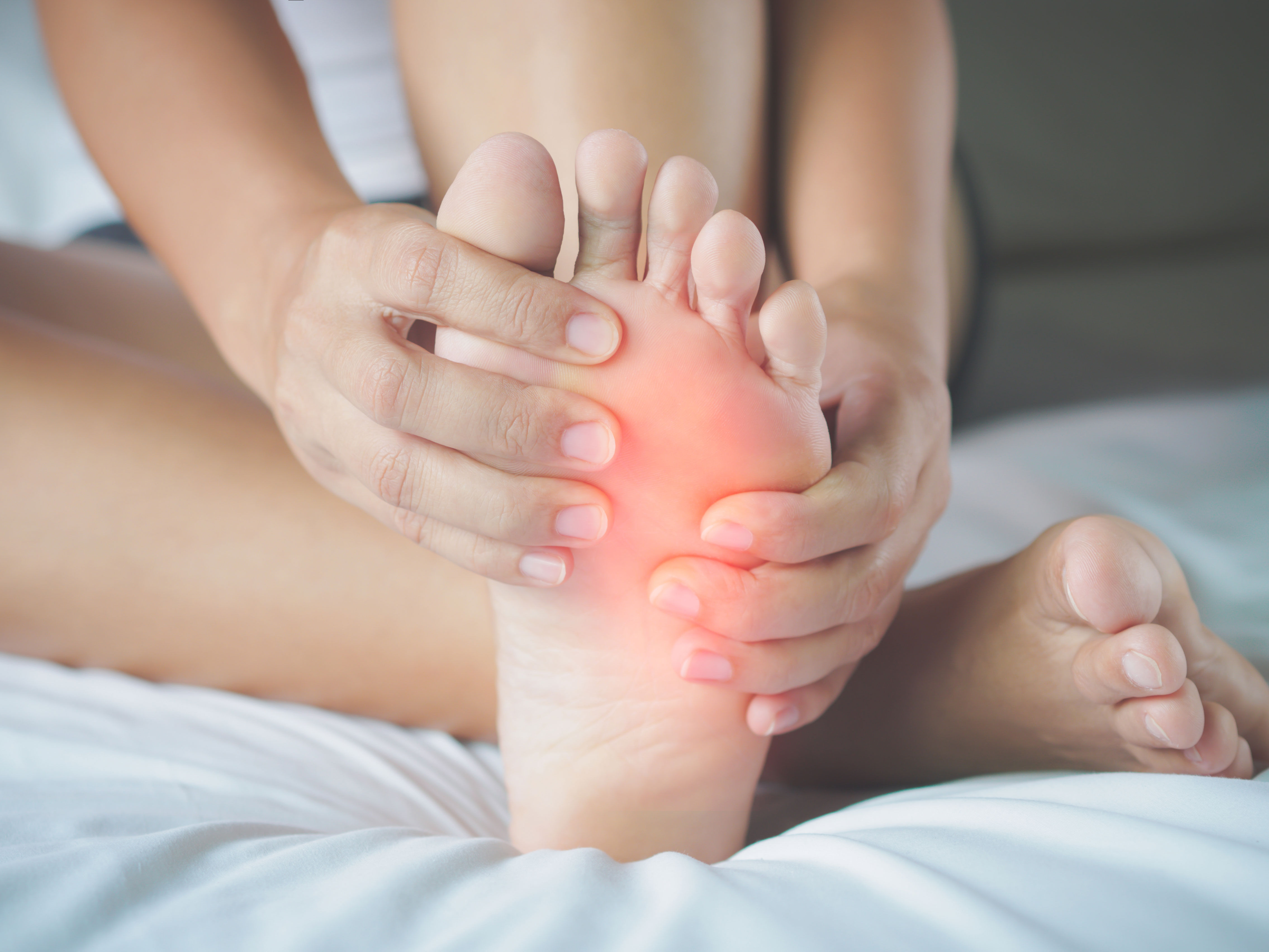 person holding their foot with red light overlaid to show pain location