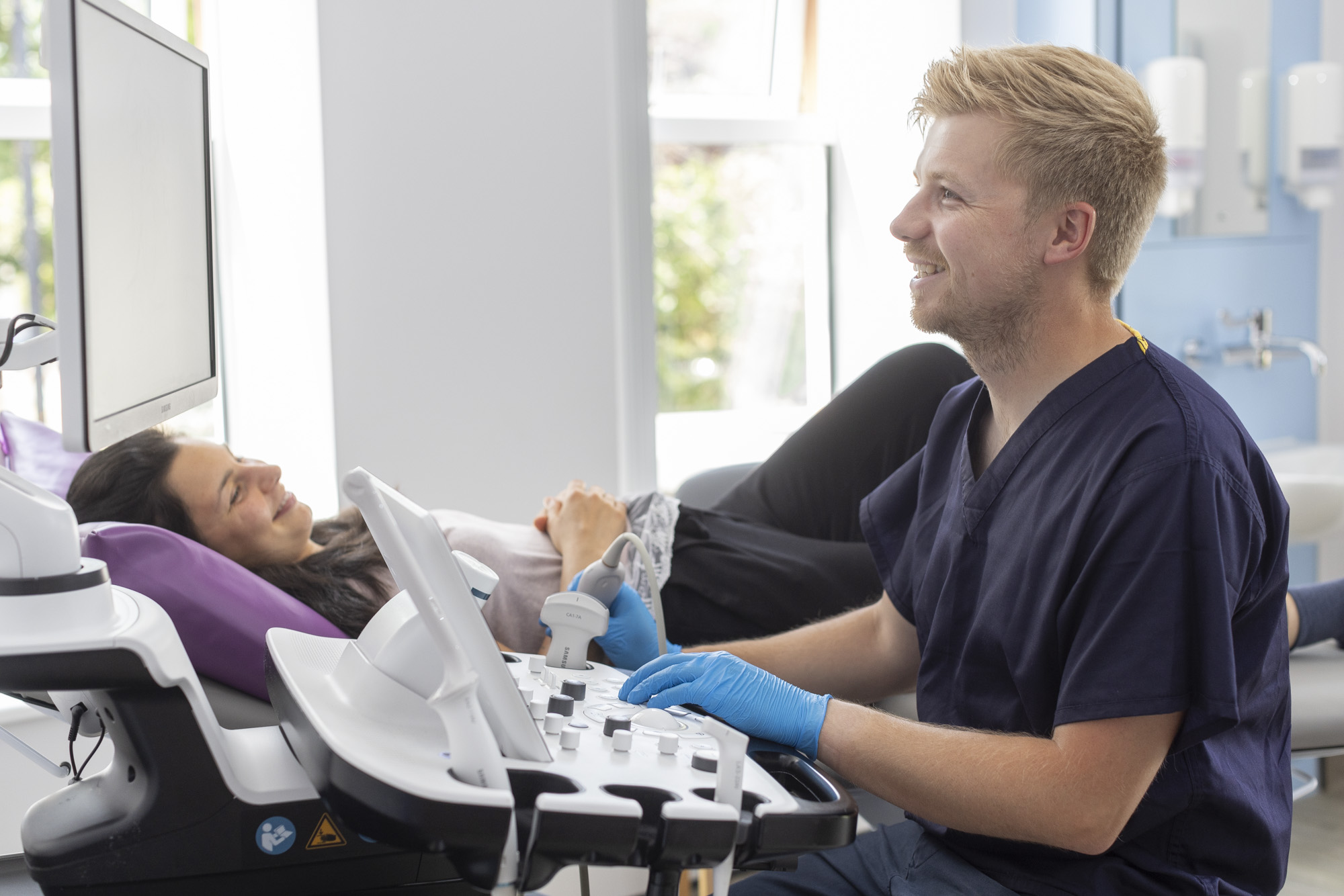 sonographer with patient both smiling during ultrasound scan