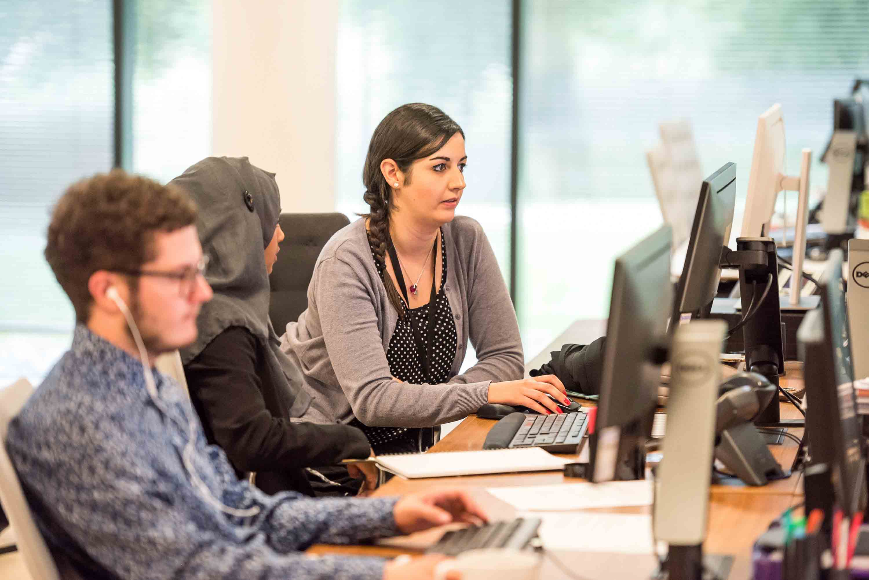 woman at work looking at computer with her colleagues