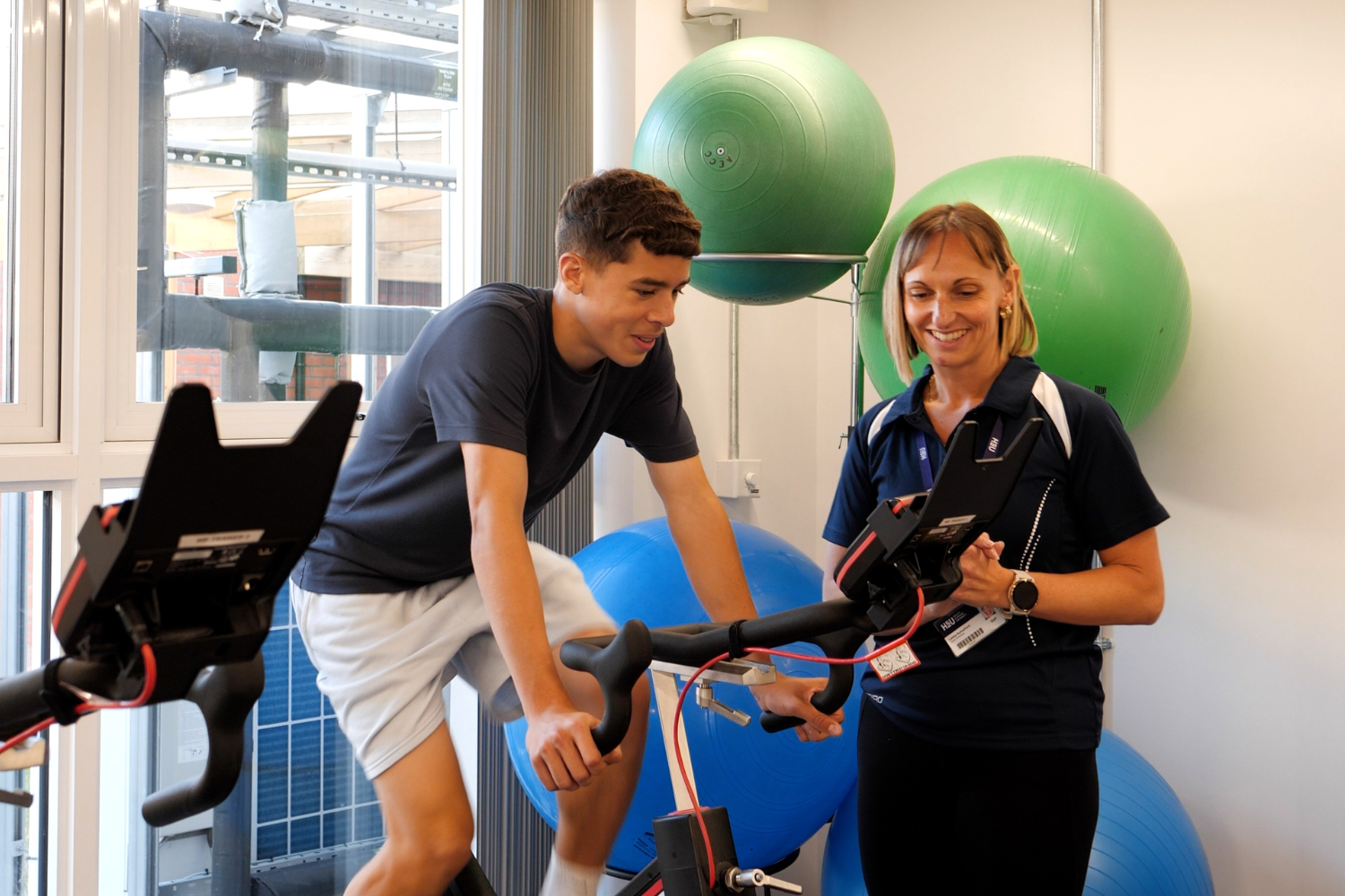 Sports therapist advising patient on exercise bike